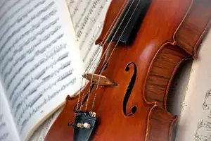 A violin lying on top of some music notes.